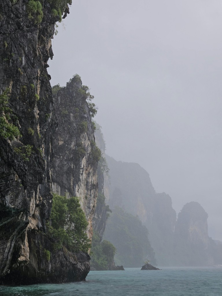 Dramatic limestone cliffs rising from the ocean in misty Krabi, Thailand.
